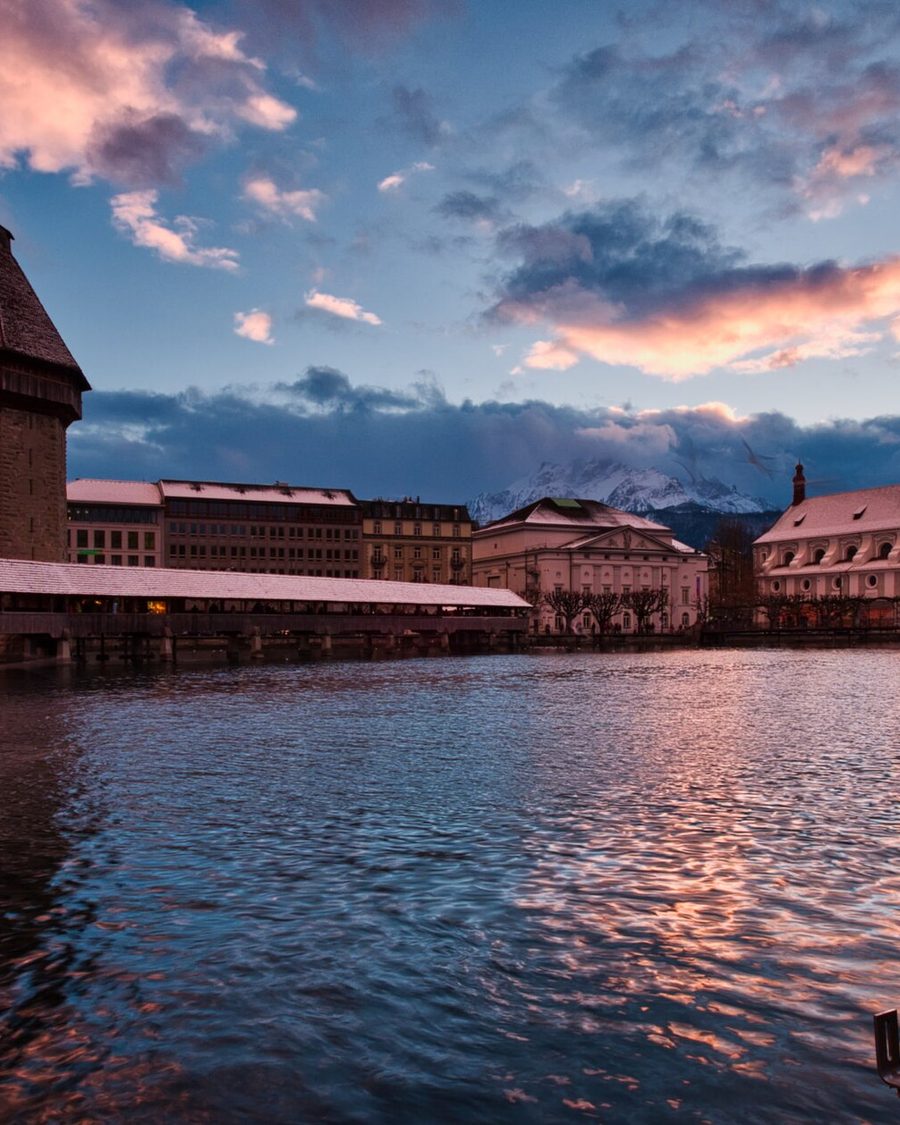 Lucerne Chapel Bridge and snow-capped mountains at dusk